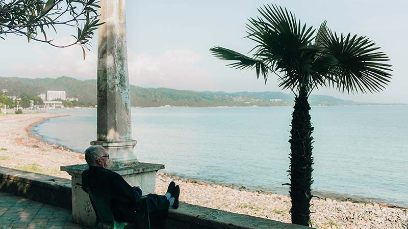 An investor relaxing while sitting on the seashore after his retirement