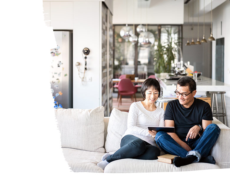 Couple is sitting on couch and using tablet.