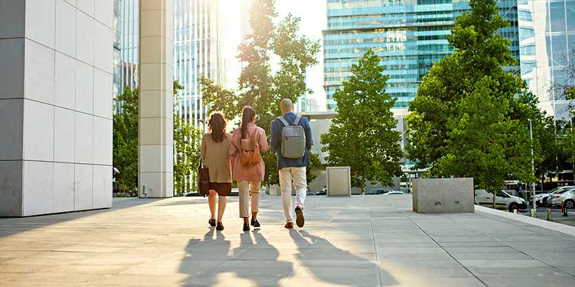 Full length rear view of male and female professionals walking across business park esplanade.