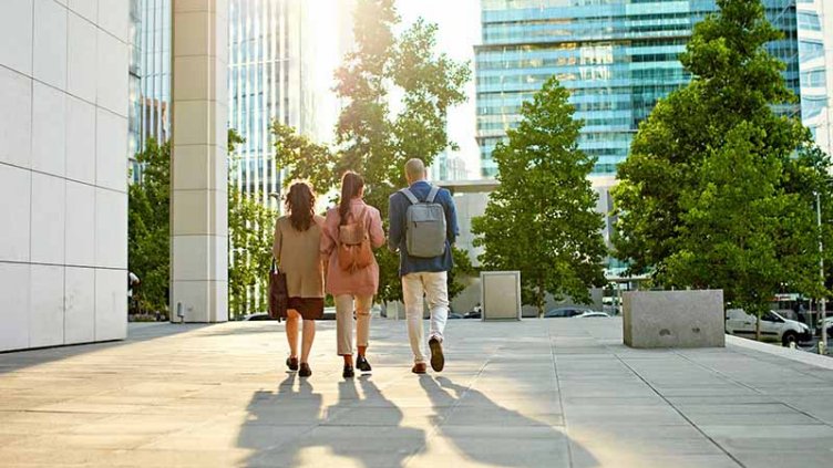 Full length rear view of male and female professionals walking across business park esplanade.