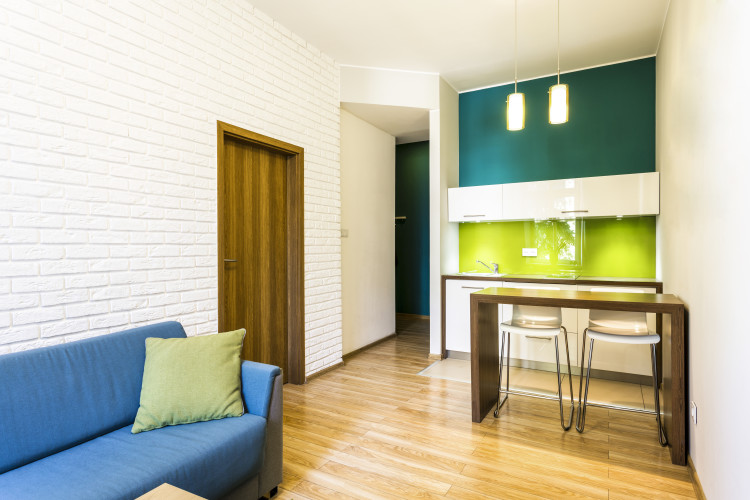 Small living room with brick wall and green kitchenette