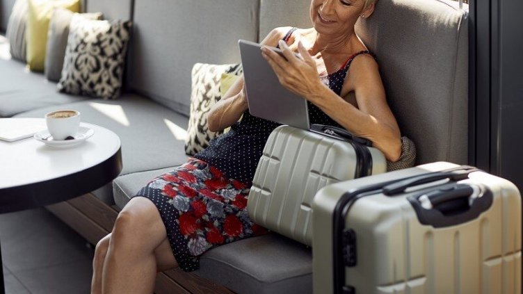 A woman using her tablet while waiting in the hotel with her luggage