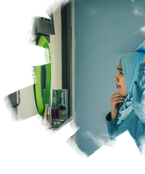 A woman is getting ready and looking towards the mirror in her house